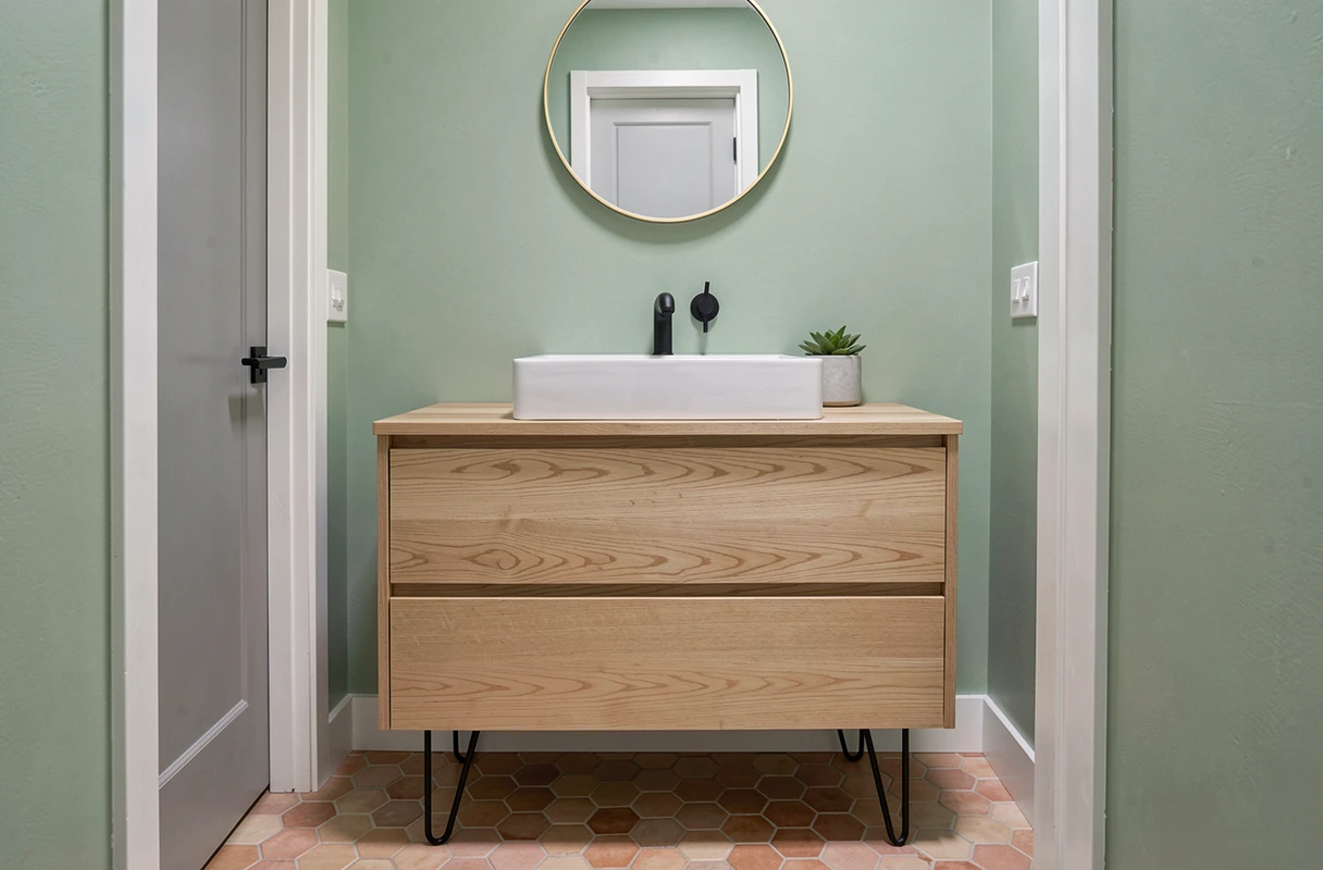Meuble sous vasque en palette vernie avec pieds en épingle à cheveux noirs dans une salle de bains style scandinave vert sauge